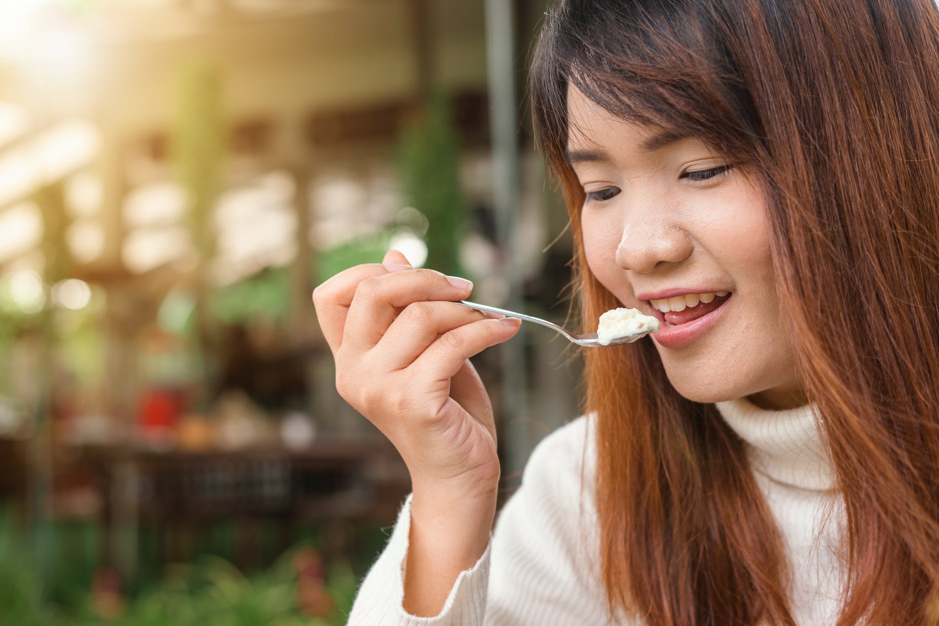 woman holding spoon trying to eat white food
